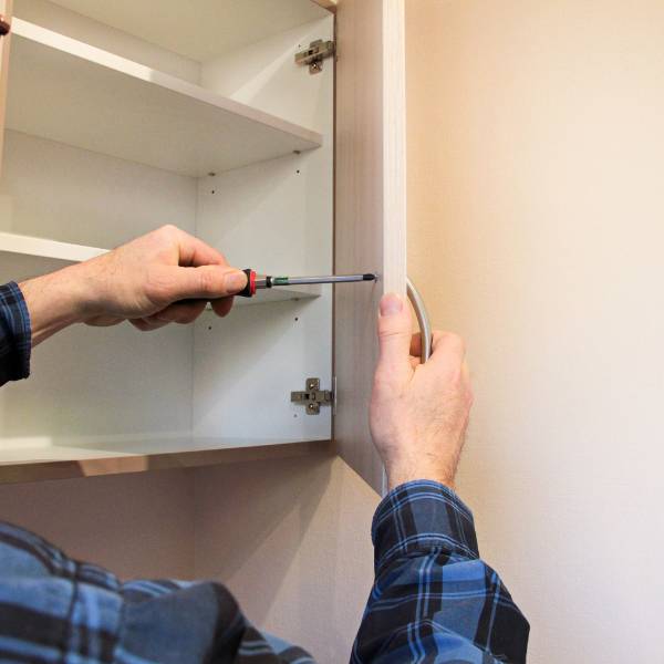 Sorgfältiges Einstellen eines Scharniers bei der Schrankmontage.